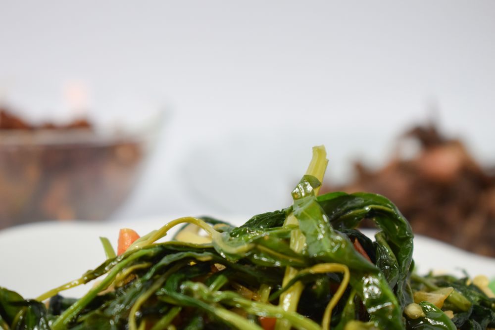 Plate of cooked greens side dish on table with copy space