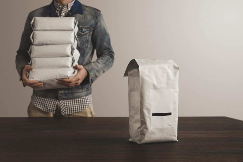 Man holding bags of coffee beans with one in the foreground
