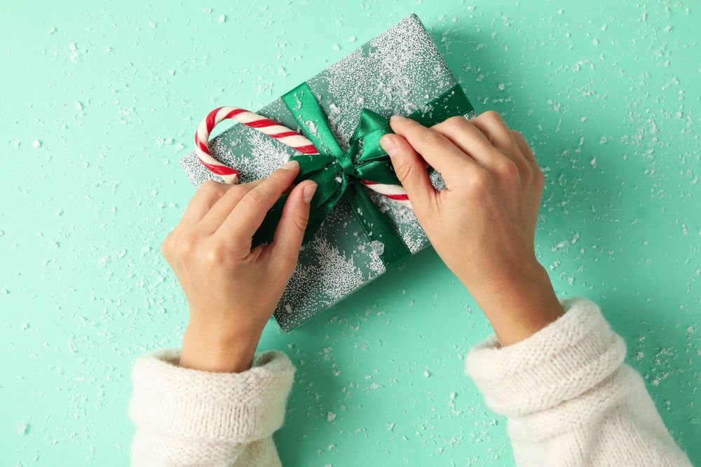 Female hands open the gift box on mint background
