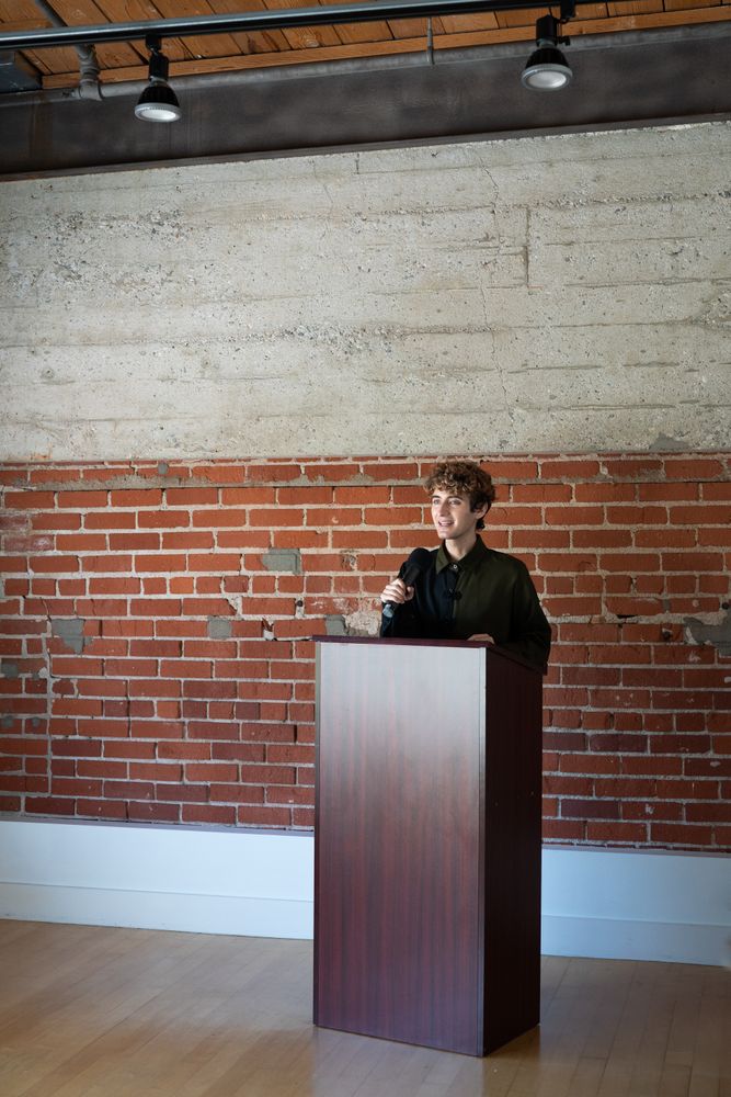 Nonbinary person standing at podium with microphone