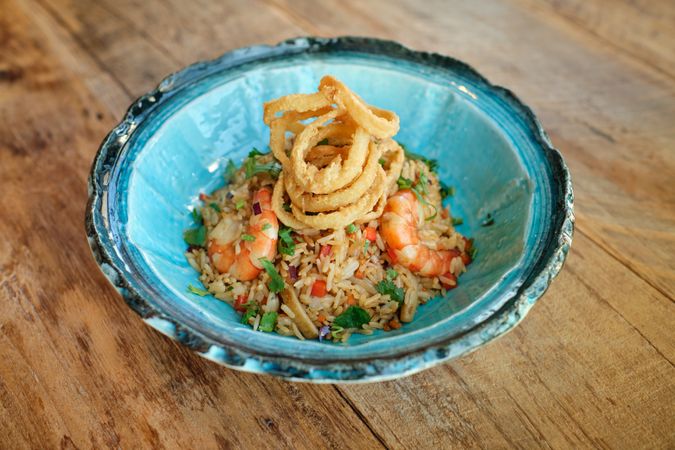 Bowl of delicious fried rice with shrimps on wooden table