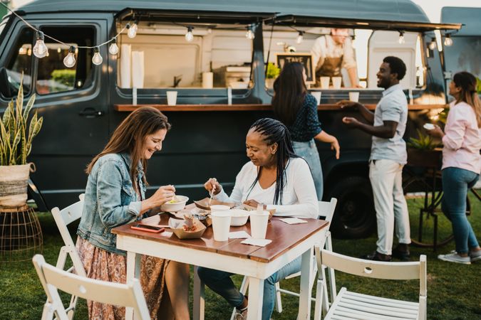 Diverse women having lunch in park near food truck