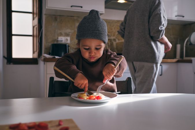 Little boy eating pancake with banana and strawberry