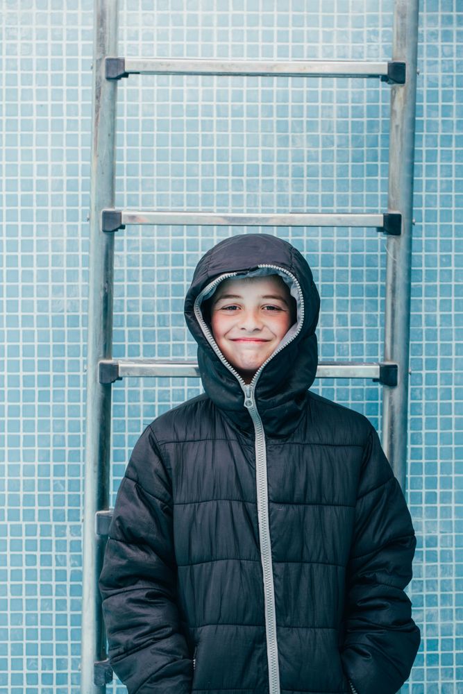 Boy in warm clothes standing in empty pool