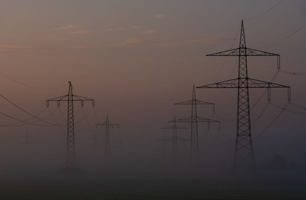 High voltage towers in a row on a foggy morning in a german village
