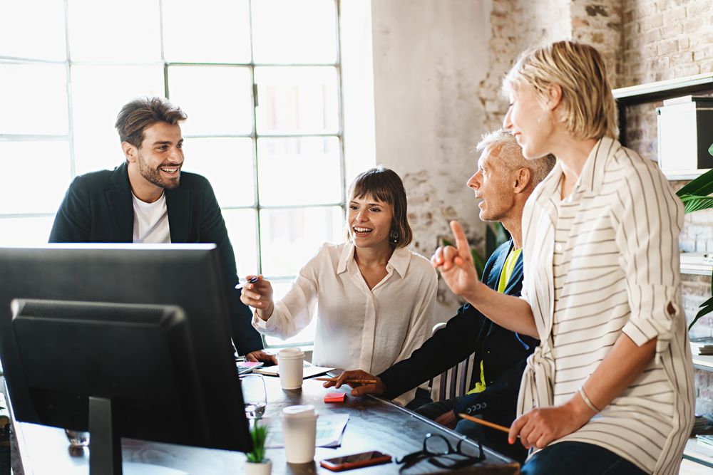 Creative business team sharing laptop in office, watching startup presentation