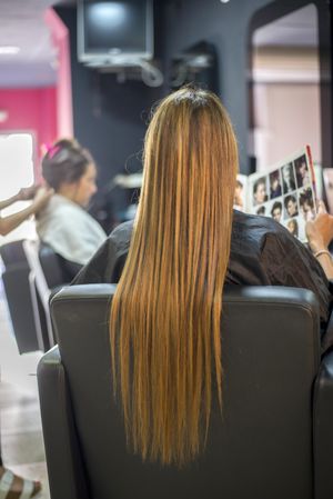 Back of woman with very long hair sitting in salons awaiting a hair cut