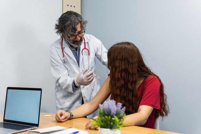 Doctor putting injection to woman patient