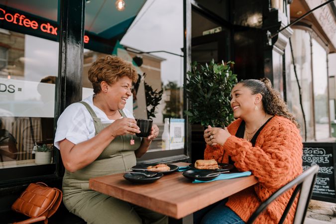 Mother and daughter enjoying sandwiches at outdoor table at cafe