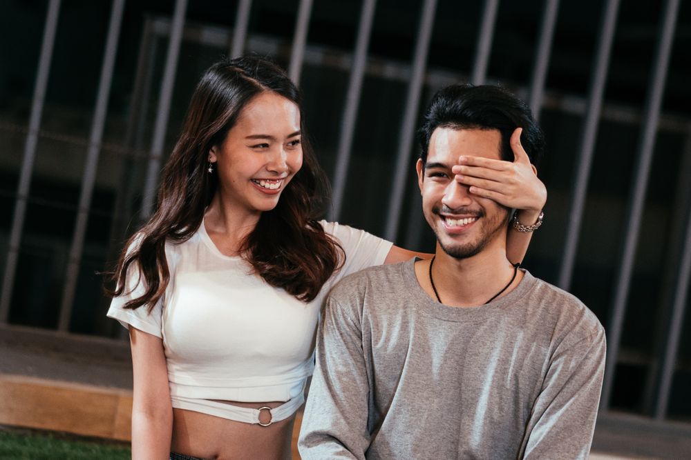 Woman with hand over boyfriend's eyes to surprise him