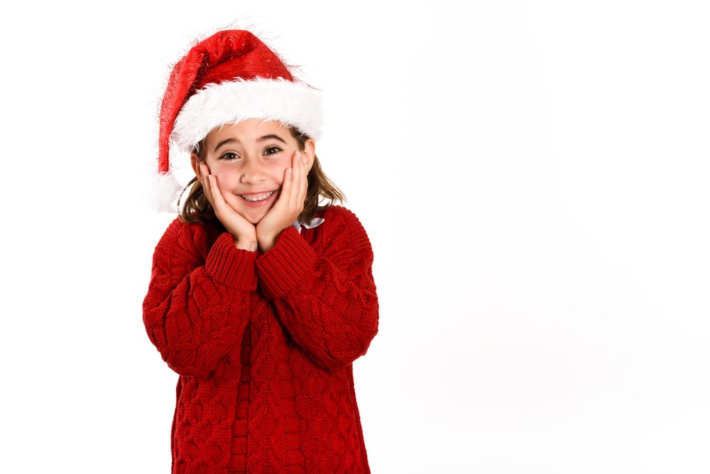 Happy girl in red Santa outfit with both hands on either side of her face