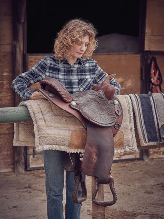Woman putting saddle on railing