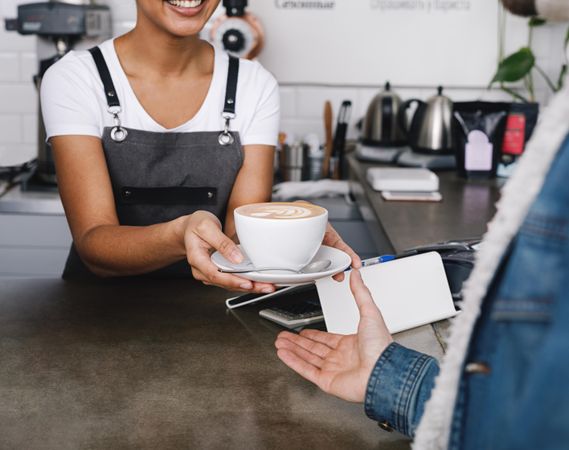 Woman handing cappuccino to customer