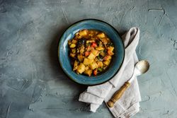 Top view of Georgian summer and autumnal dish Ajapsandali with vegetables in blue bowl