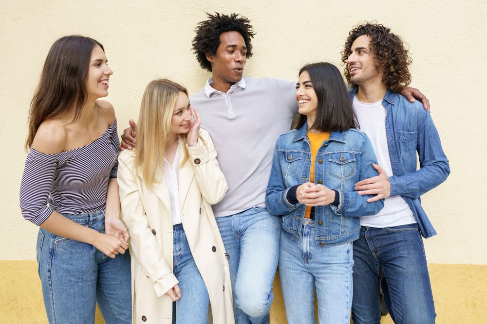 Happy group posing for portrait leaning against a yellow wall