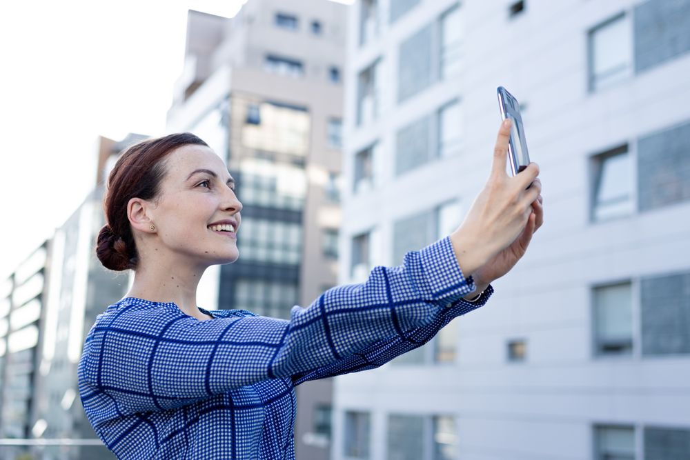 Smiling businesswoman taking selfie on street