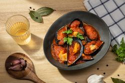 Cooked plate of mussels in tomato sauce on table