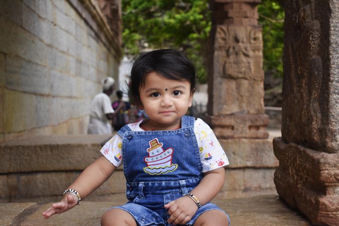 Indian child in denim wear sitting on the ground