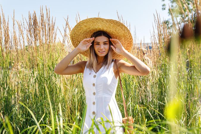 Calm happy female in a field outside wearing a sunhat and dress