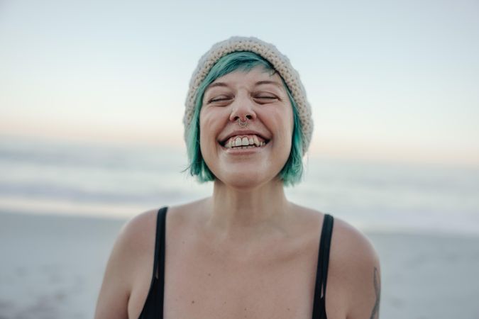 Cheerful winter bather smiling with her eyes closed while standing by the sea
