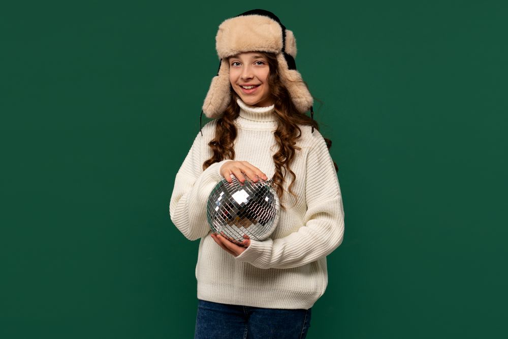 Smiling girl in winter hat holding small disco ball.