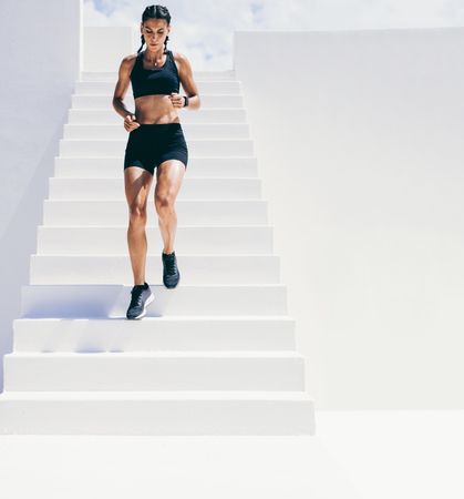 Female athlete running down stairs of building