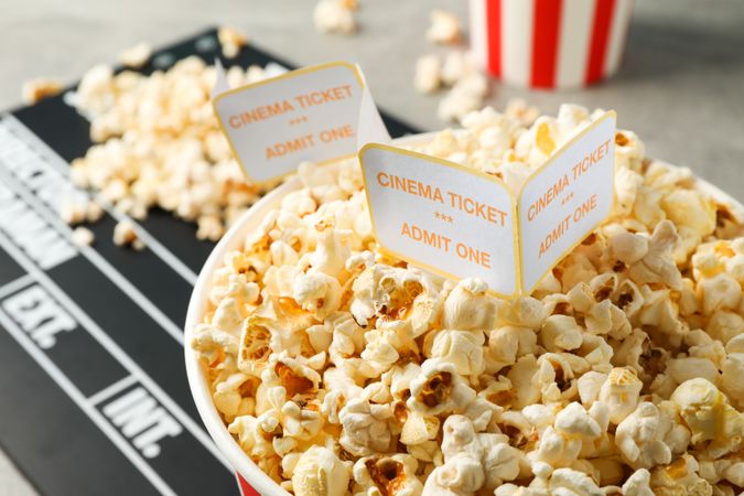 Clapperboard, tickets and buckets with popcorn on grey background, top view