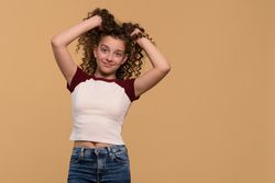Young girl playfully holding hair up, smiling cheerfully