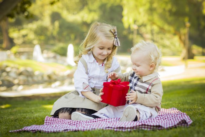 Little Girl Gives Her Baby Brother A Gift at Park.