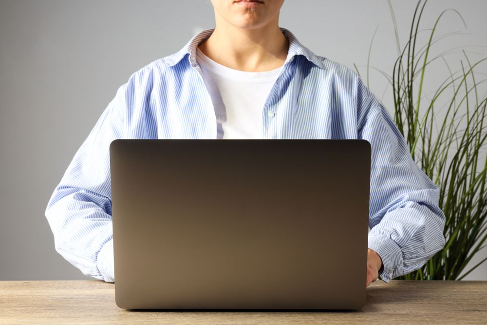 A man in a shirt works at a laptop