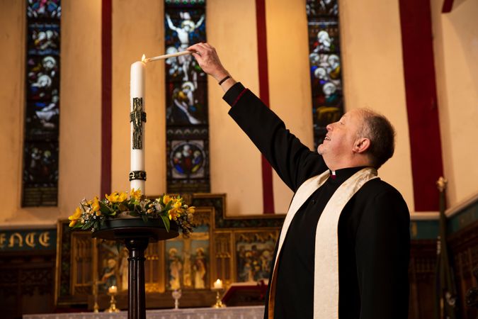 Vicar lighting candle in church