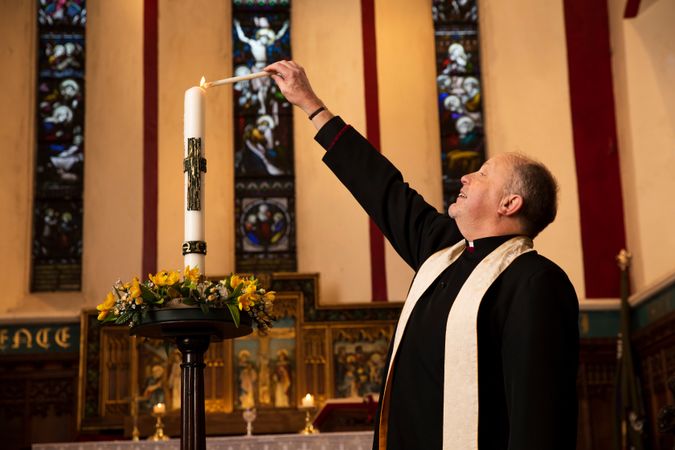 Vicar lighting candle in church