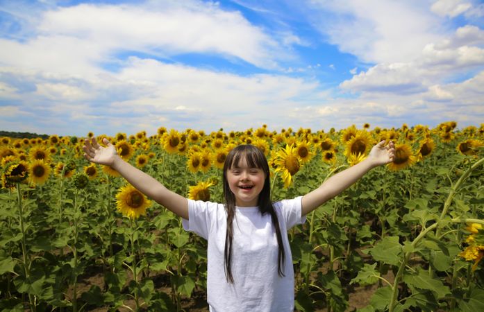 Excited young girl with Down syndrome standing in a flower field