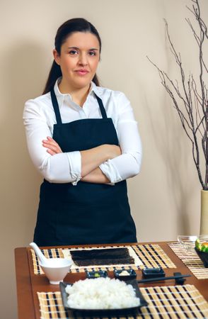 Sushi chef posing in front of table with cooking preparations