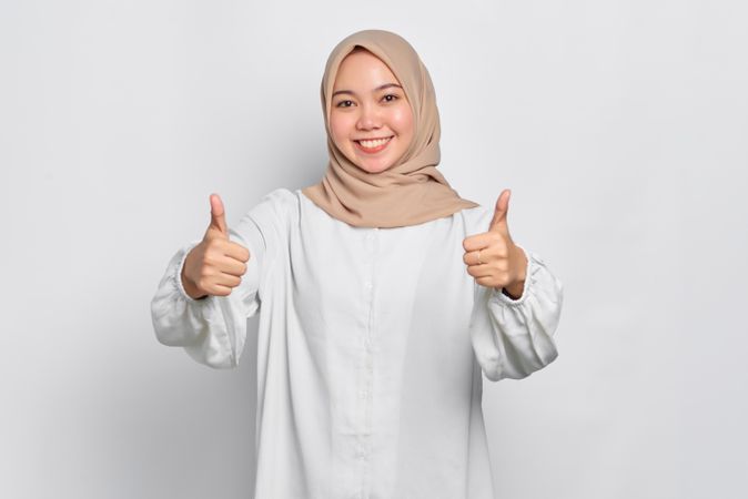 Asian female in headscarf with both thumbs up