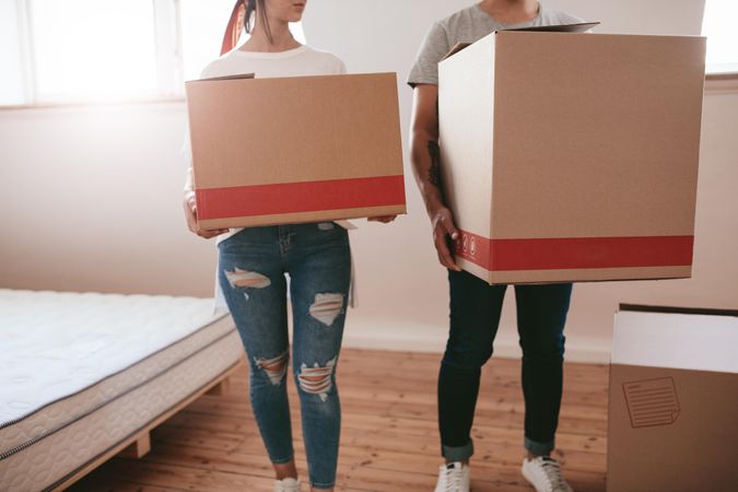 Cropped shot of man and woman carrying boxes and moving into new house