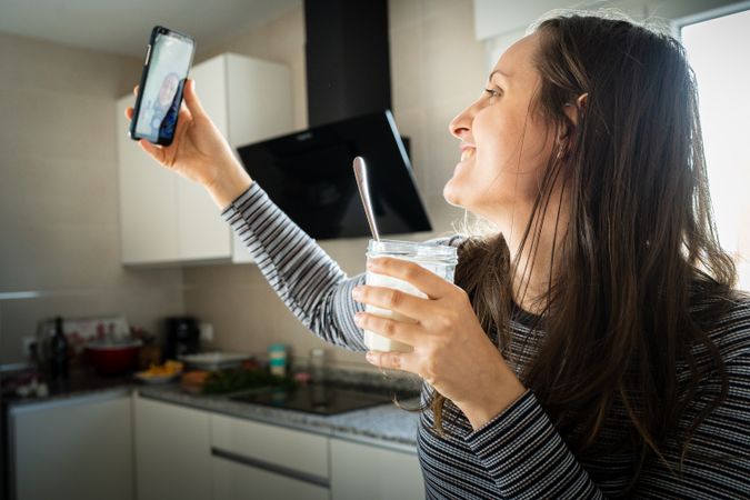 Cheerful woman taking selfie with yogurt