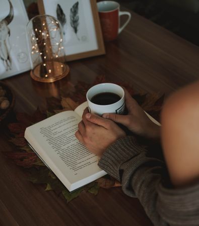 Cropped image of woman enjoying a coffee and reading a book