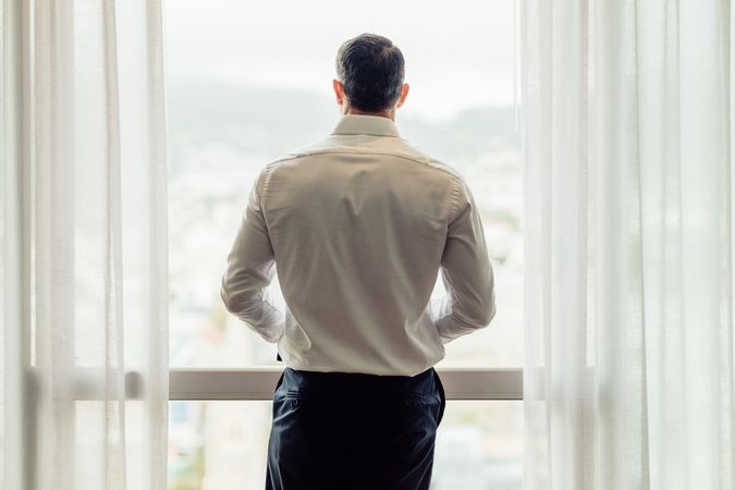 Businessman standing at hotel room window