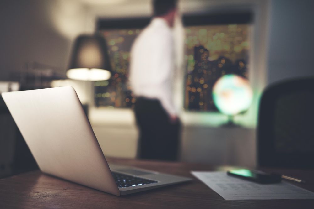 Laptop and paper with business man in background
