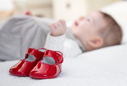 Baby red shoes and babe lying on the background