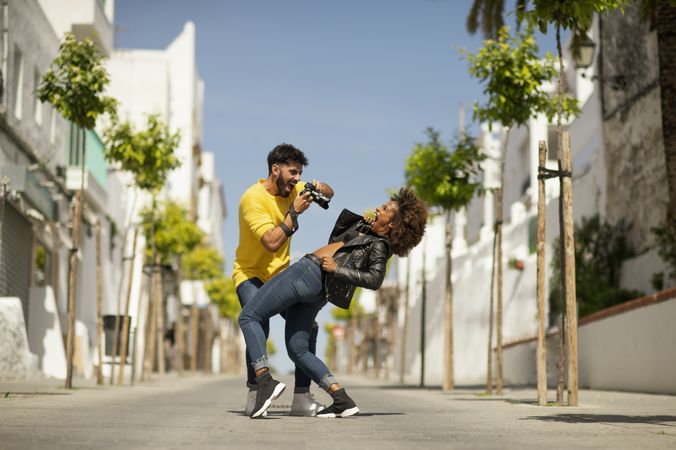 Excited man taking photo of bending girlfriend