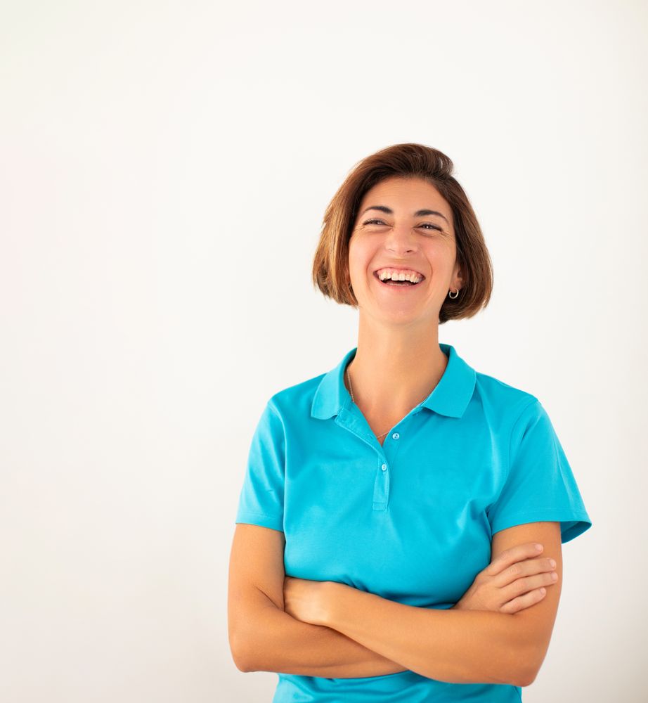 A woman, owner of her own physiotherapy clinic, smiles confidently, on a plain white background