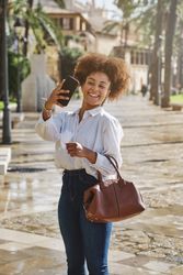 Positive Black female taking selfie on street