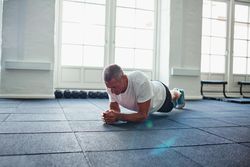 Man planking alone in bright gym