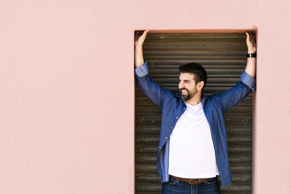 Man in denim smiling in pink doorframe