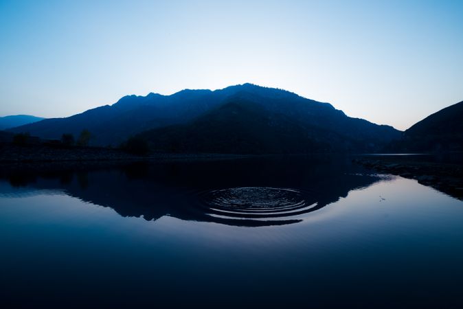 Picturesque view of water surface near amazing rock hills at sunset and blue sky