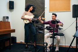Man playing guitar and woman playing drums