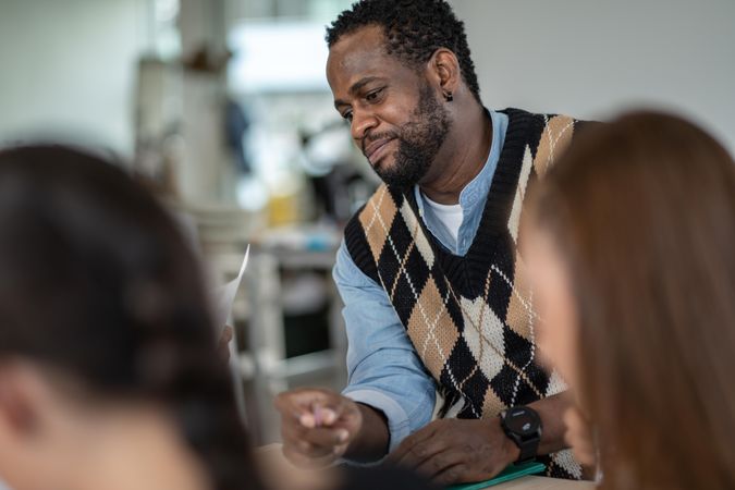 Focused male teacher with students in classroom holding pencil