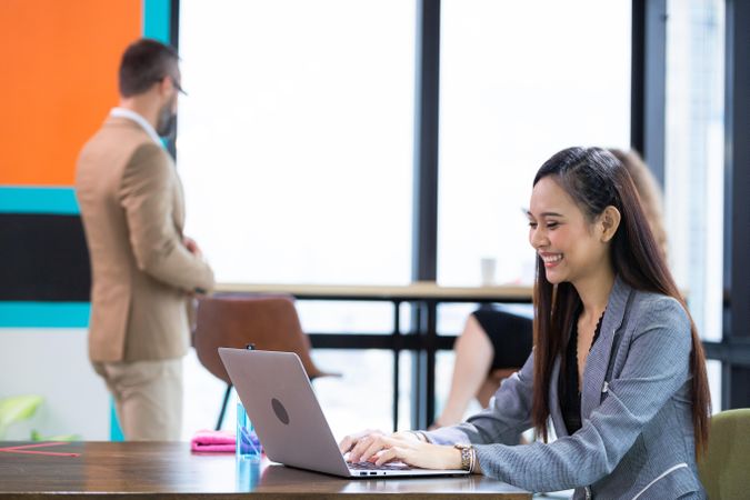 Asian female employee using computer laptop working in busy office